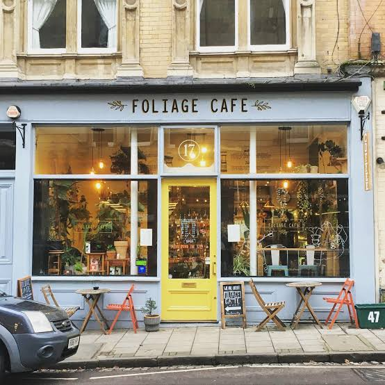 The Foliage Cafe shopfront on Regent Street: pale blue frontage, a yellow door under a 17 fanlight, and folding chairs on the pavement